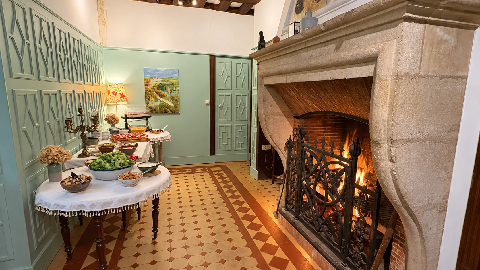 Un buffet installé dans la salle aux boiseries vertes et à la grande cheminée